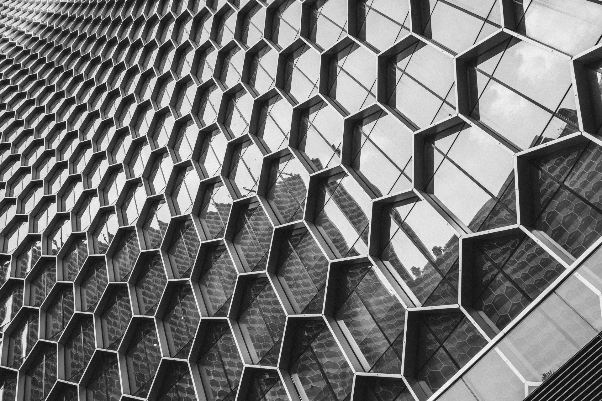 Black and white image of a modern building facade with a geometric hexagonal pattern.