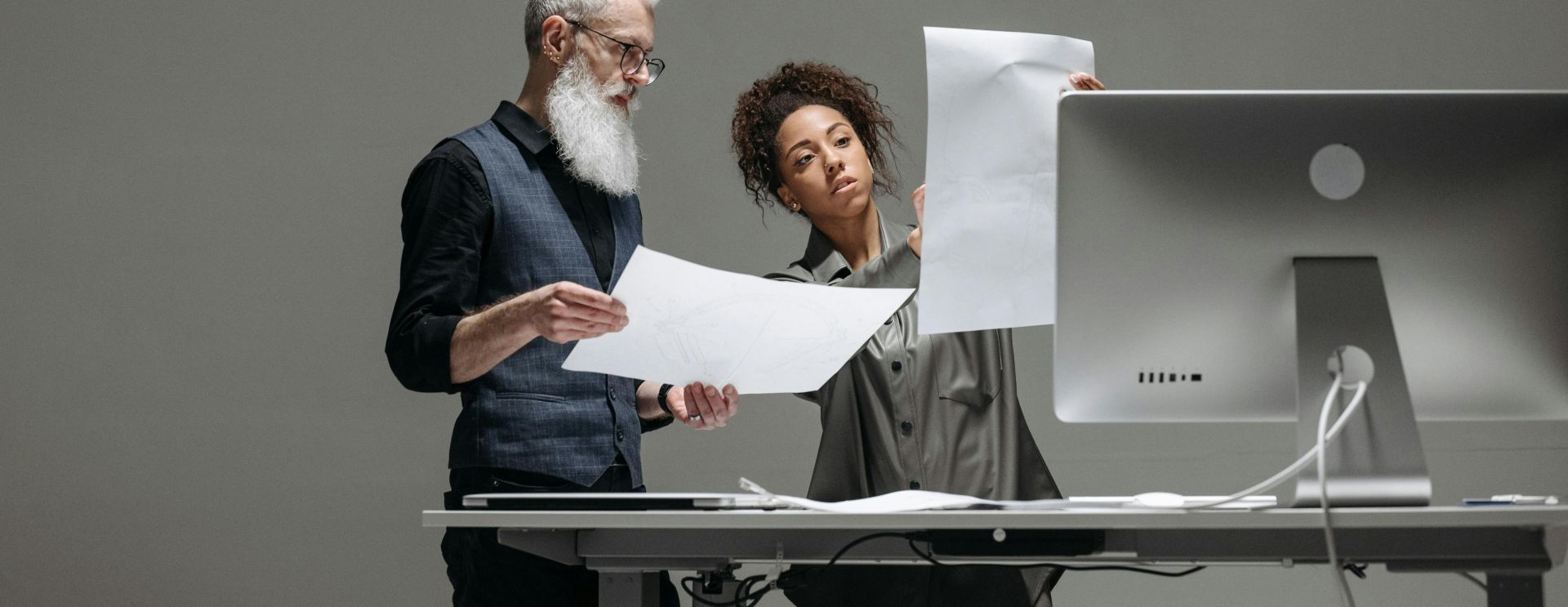 Two professionals collaborate on project plans at a computer workstation.