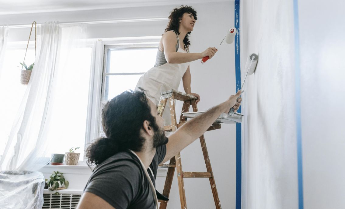 A couple engaged in a joyful home renovation, painting walls together.